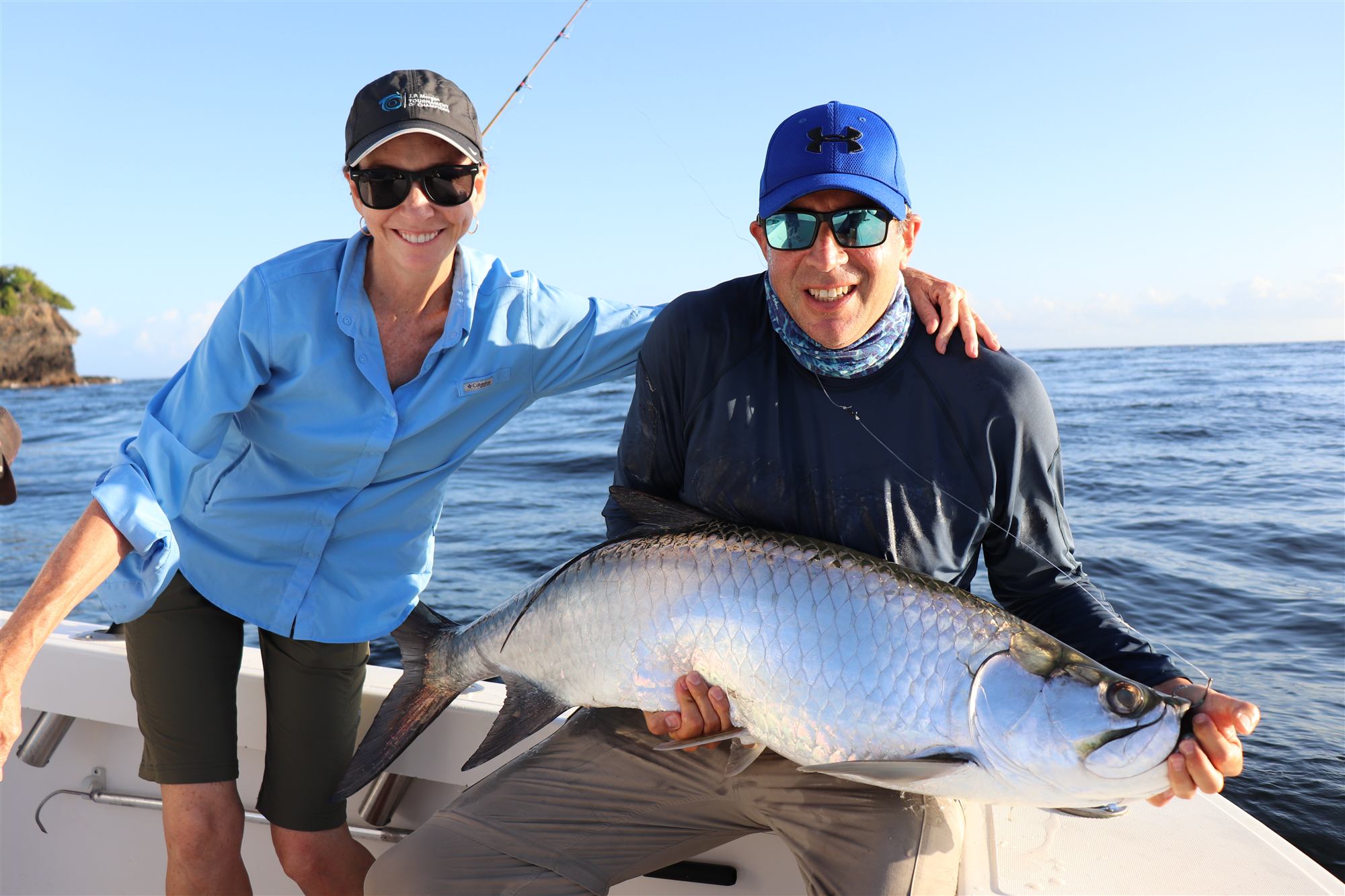 Two anglers on a boat with a large silver tarpon, open ocean behind